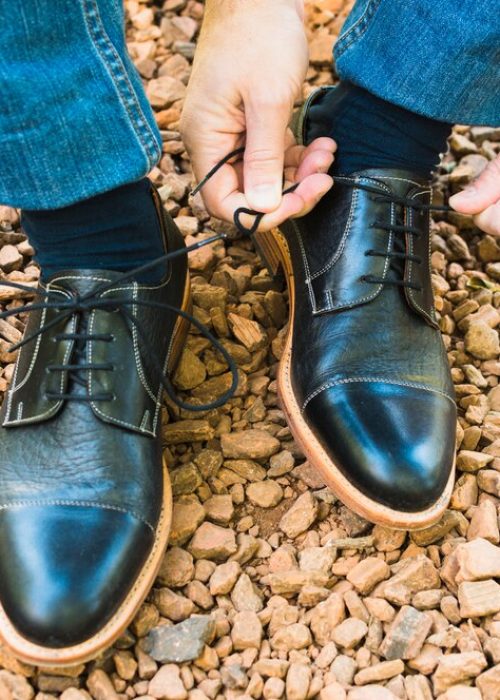 elevated-view-man-s-foot-pebble-tying-shoelace_23-2148164524